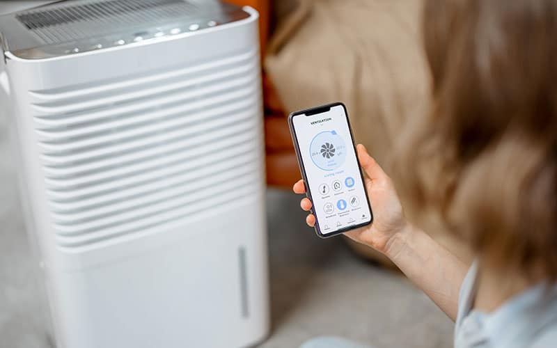 Woman with smart phone controlling HVAC unit