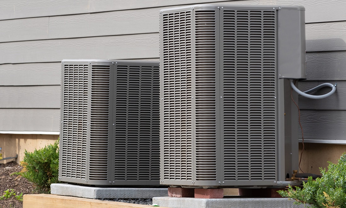 Two air conditioner units on the side of a home